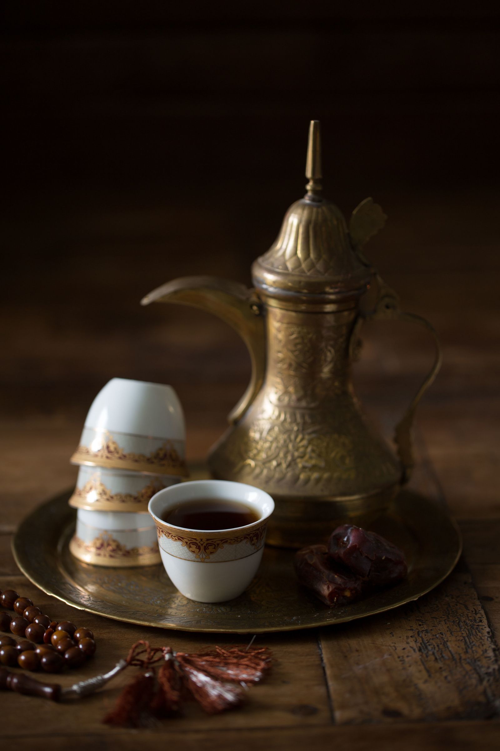 A bronze pot of Arab coffee next to some dates and two ceramic cups at 1001 Nights luxury sustainable restaurant